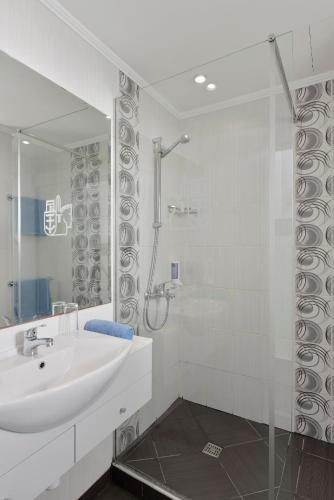 a white bathroom with a sink and a shower at Napa Prince Hotel Apts in Ayia Napa