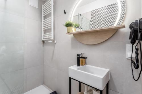 W białej łazience znajduje się umywalka i lustro. w obiekcie Warsaw City Apartments Stadion Narodowy w Warszawie