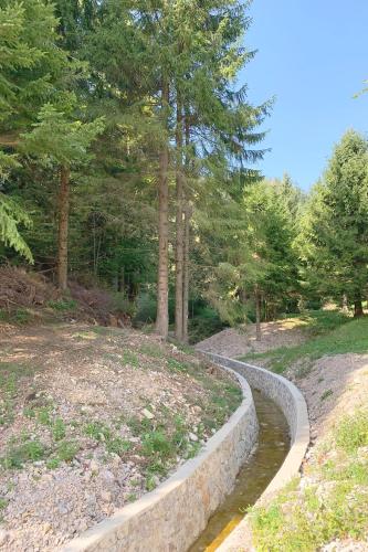 a stone wall next to a pond in a park at NOOK studio apartman Lokve in Lokve