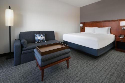 Habitación de hotel con cama y sofá en Courtyard Dallas Las Colinas, en Irving