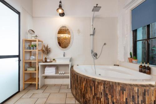 a bathroom with a large tub and a mirror at Trieste Neve Tzedek Boutique Suites Tel Aviv in Tel Aviv