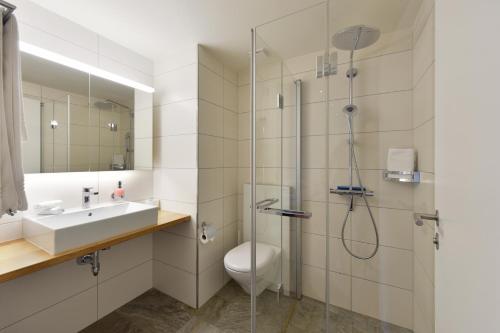 a bathroom with a shower and a toilet and a sink at Hotel Sternen in Lenk