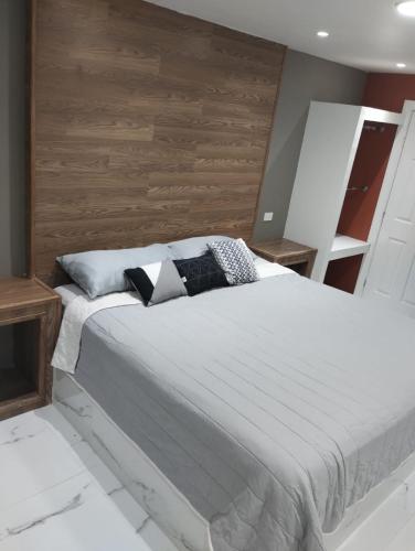 um quarto com uma cama branca e uma parede de madeira em HABITACION SENCILLA CAMA KS Y BAÑO em Ciudad Juárez
