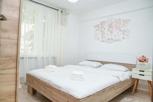 um quarto branco com uma cama e uma janela em L'escale - Ultracentral em Craiova