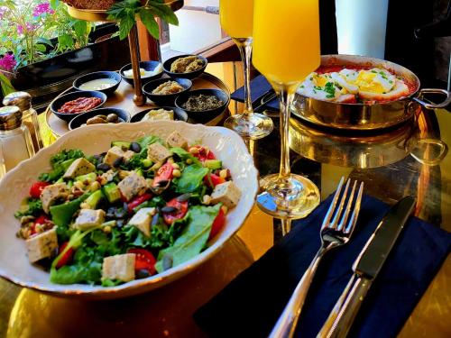 a table with a salad and a plate of food at The Rothschild Hotel - Tel Aviv's Finest in Tel Aviv