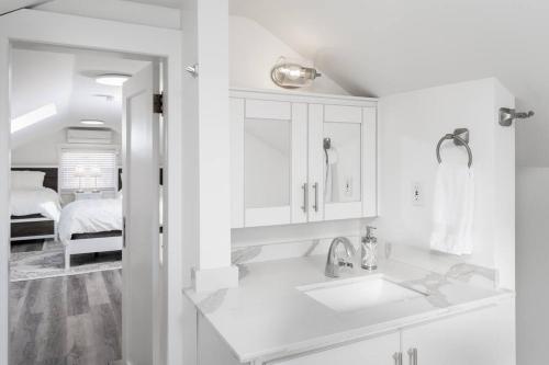 a white bathroom with a sink and a bed at Alexander Beach House Okanagan in Penticton