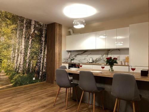 a kitchen with a kitchen island with chairs and a tree mural at Parkcity Kraków pro in Krakow