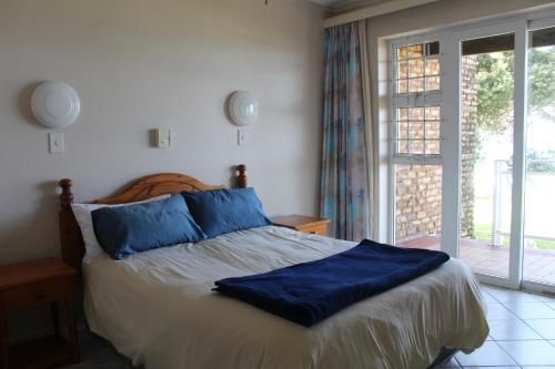ein Schlafzimmer mit einem Bett mit blauen Kissen und einem Fenster in der Unterkunft Anguna Holiday Flats in Margate