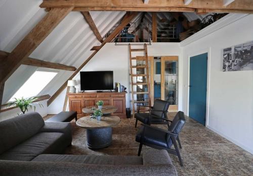 a living room with a couch and a table and chairs at De hooizolder Hofstay195 in Achterveld