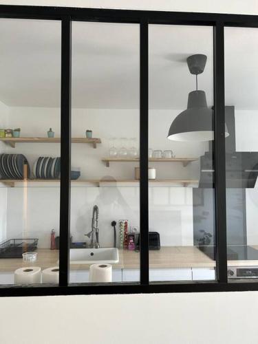 uma cozinha com uma janela com um lavatório e um balcão em Jolie cosy appartement de 52m2 em Asnières-sur-Seine