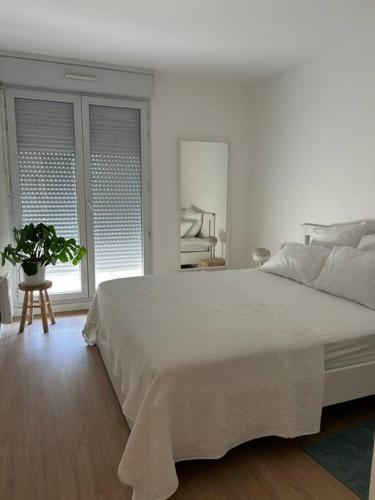 - une chambre blanche avec un grand lit et une plante en pot dans l'établissement Appart Cosy de 52m2, à Asnières-sur-Seine