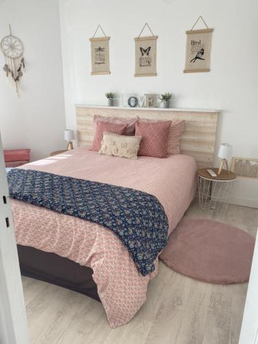 a bedroom with a large bed with pink and blue sheets at L’appart in Lisieux