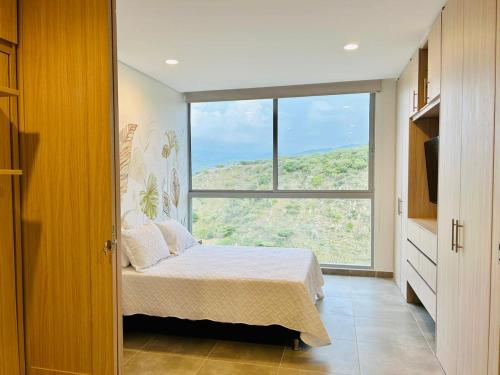 1 dormitorio con cama y ventana grande en Salguero Suites - Playa Salguero - By INMOBILIARIA VS en Santa Marta