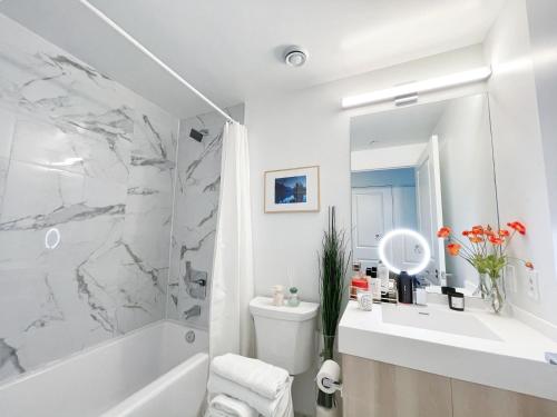 La salle de bains blanche est pourvue d'une baignoire blanche et d'un lavabo. dans l'établissement INFIVILLA Amazing Penthouse Living in Sunrise- Breathtaking Skyline Lake View Downtown Toronto!A, à Toronto