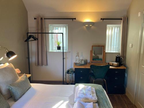 a bedroom with a bed and a desk with a mirror at Blue Ball Inn, Sandygate, Exeter in Exeter