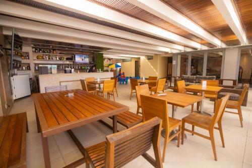 un restaurante con mesas y sillas de madera y un bar en Riale Brisa Barra, en Río de Janeiro