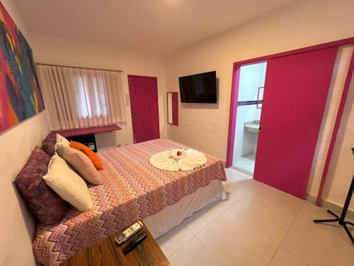 a bedroom with a bed and a tv and a room at Pousada Refúgio de Maresias in Maresias