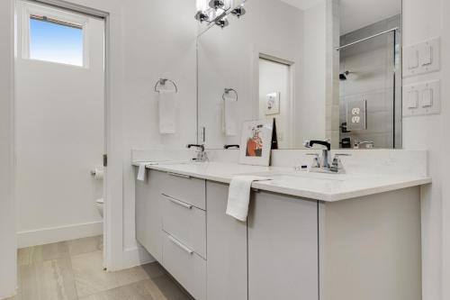 a white bathroom with two sinks and a mirror at EastSide Rooftop Oasis in Austin
