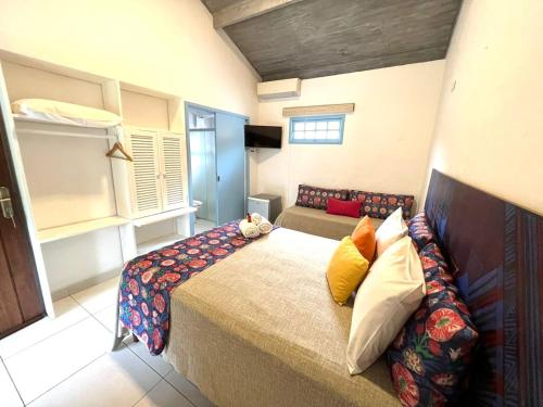 a bedroom with a large bed with colorful pillows at Pousada Refúgio de Maresias in Maresias