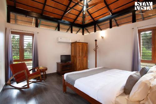 a bedroom with a bed and a desk and a tv at StayVista at Ava - The Country House with Breakfast & Miniature Golf in Mysore