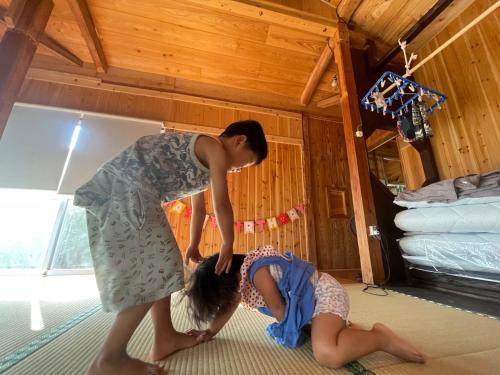 twee mensen in een kamer met een vrouw op de vloer bij 一棟貸しの移住案内古民家　itoma in Setouchi