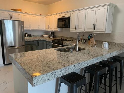 a kitchen with a granite counter top and black bar stools at Condominio en Bahia Delfin in San Carlos
