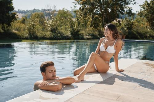 a man and a woman sitting in a swimming pool at Borgo Lanciano in Castelraimondo