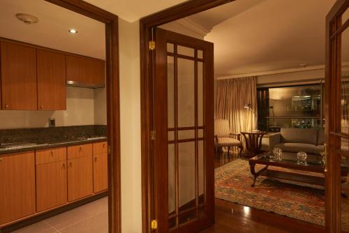 a kitchen with wooden cabinets and a living room at Plaza El Bosque Ebro in Santiago