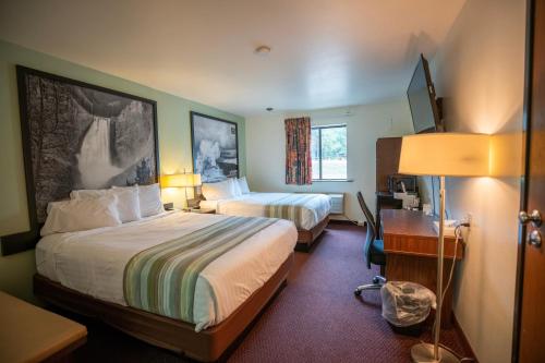 a hotel room with two beds and a desk at Mountain Vista Hotel in West Yellowstone