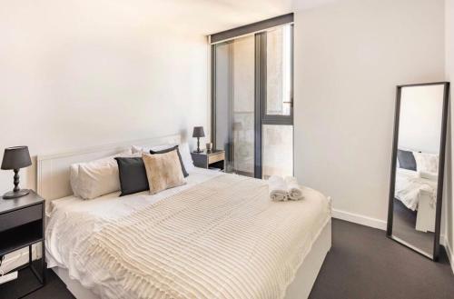 ein Schlafzimmer mit einem großen weißen Bett und einem großen Spiegel in der Unterkunft Spacious Apartment in the CBD in Melbourne
