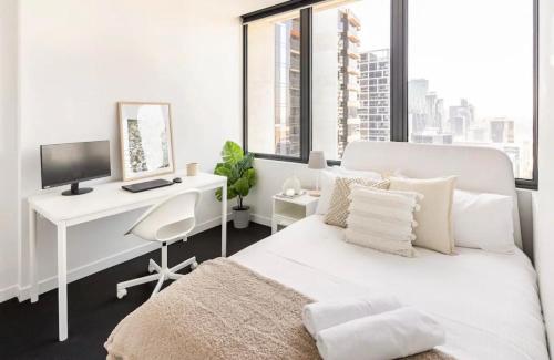 ein weißes Schlafzimmer mit einem Schreibtisch und einem Bett in der Unterkunft Spacious Apartment in the CBD in Melbourne