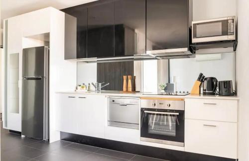 eine Küche mit weißen Schränken und einem Kühlschrank aus Edelstahl in der Unterkunft Spacious Apartment in the CBD in Melbourne