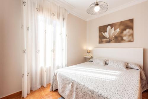 1 dormitorio con cama blanca y ventana en CASA ANGELITA Caminito del Rey, Apartamento con cocina en el centro de Andalucía, en Valle de Abdalajís