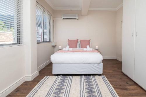 Habitación blanca con cama y alfombra en Two bedroom Apartment on kloof en Ciudad del Cabo
