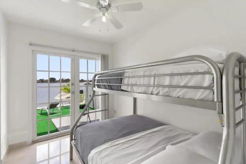 Ce lit superposé se trouve dans un dortoir blanc doté d'une fenêtre. dans l'établissement Lakeside 3br Retreat With Private Yard & Kayak Use, à Fort Lauderdale