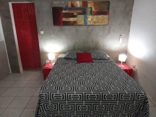 een slaapkamer met een groot bed en 2 rode tafels bij La Villa Les Cythos 1 in Le Lamentin