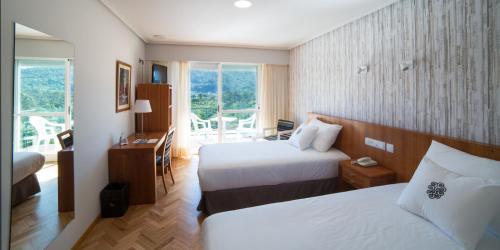a hotel room with two beds and a balcony at ARNOIA CALDARIA HOTEL Y BALNEARIO in Arnoia