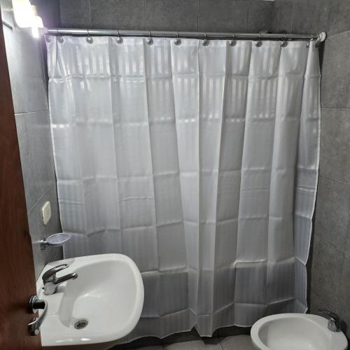 uma casa de banho com uma cortina de chuveiro branca e um WC. em Vintage em La Plata