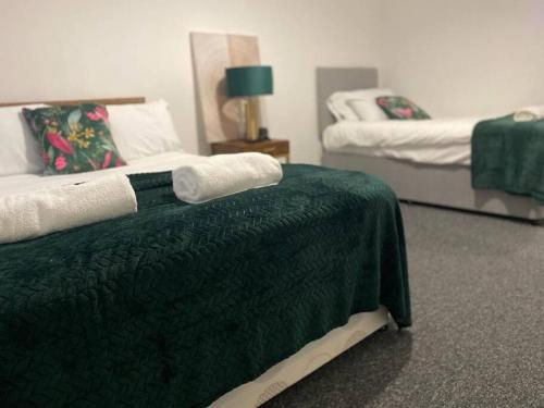 a bedroom with two beds with green sheets and a green blanket at Bridgewater Flat in Bridgwater