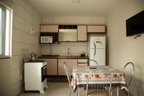 una pequeña cocina con mesa y nevera en Aloha Bratz Apartments 3, en Palhoça