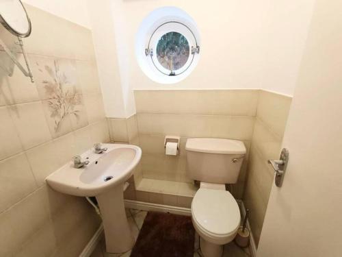 a small bathroom with a toilet and a sink at 4Bed House MK in Simpson
