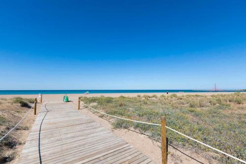 a wooden path to a beach with the ocean in the background at Romantico Apartamento en el Puerto de Denia in Denia