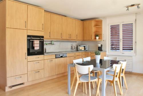 una cocina con armarios de madera, mesa y sillas en Swiss Tranquility Suites, en Aarau