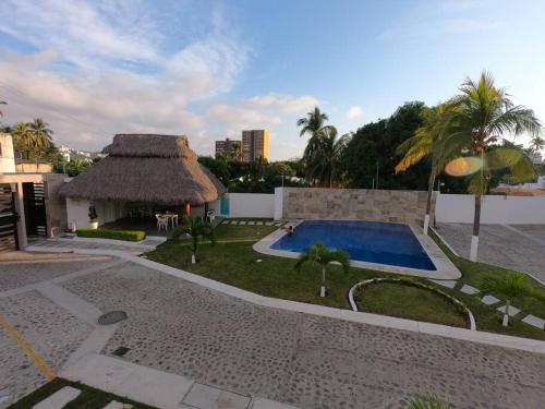 uma villa com uma piscina e um telhado de palha em Hermoso y acogedor departamento Colinas Santiago em Manzanillo