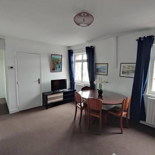 un salon avec une table, des chaises et une télévision dans l'établissement L'Arche, appartement sur les toits d'Etretat, à Étretat