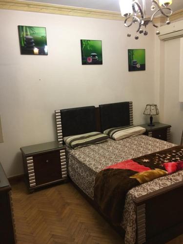 - une chambre avec un lit, une lampe et des photos sur le mur dans l'établissement zamalek, au Caire
