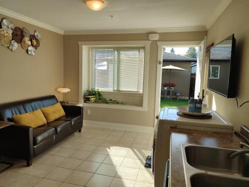 uma cozinha e sala de estar com um sofá e um lavatório em Private Suite w King Bed, Ground Level, Naturally Bright em Vancouver