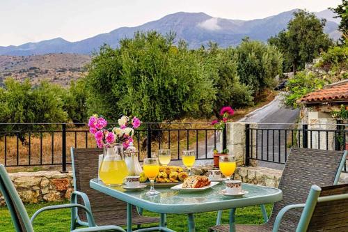 a table with a plate of food and glasses of orange juice at Pomogna house in Pemónia