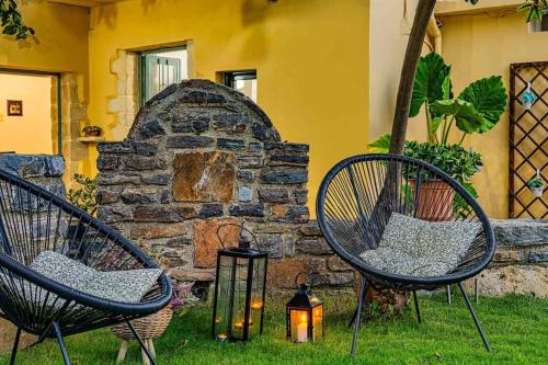 two chairs sitting in the grass next to a stone wall at Pomogna house in Pemónia