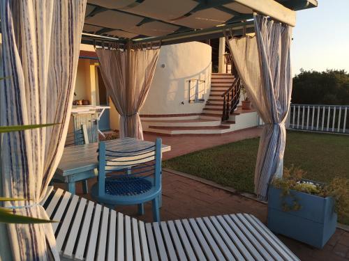 a patio with a table and chairs on a house at Nel verde del Villaggio - Casetta Celeste in Gonnesa